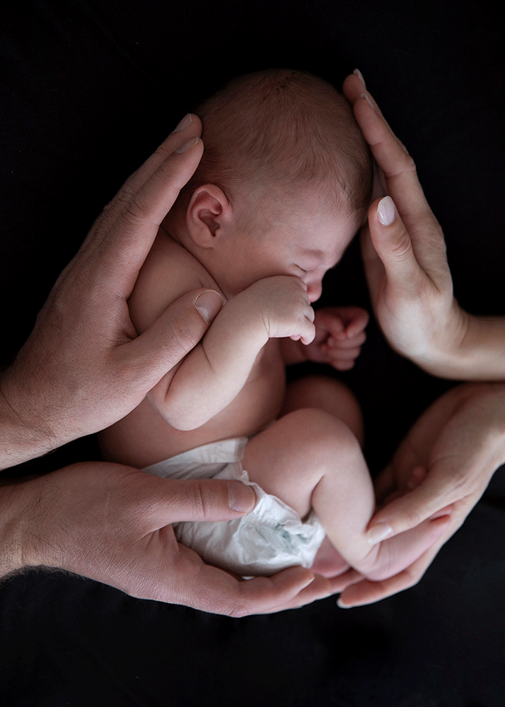 Newborn mit Geborgenheit getragen von Elternhänden